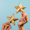 Pair of hands holding gold-dusted chocolate stars in front of a soft blue background – the sort of prize worth receiving.