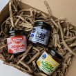 Three jars of chilli jam laying on cardboard packaging.