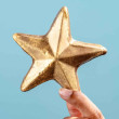 Gold-dusted chocolate star held in hand with a blue background – an edible way to say well done.
