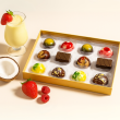 A 12 piece box of luxury chocolates with berries and a coconut on a light background