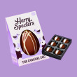 A caramel chocolate Easter egg with white chocolate swirl, in colourful packaging next to a small box of luxury chocolates