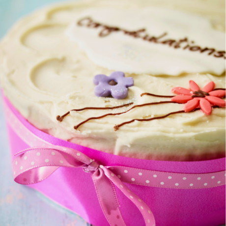 congratulations piped message with flowers on banana cake with pink ribbons