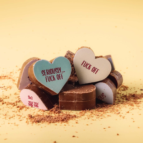 Close-up of broken Bagstock & Bumble menopause chocolates, revealing chunky slabs of Fairtrade Belgian milk chocolate – solid, satisfying, and just as bold as the messages on top.