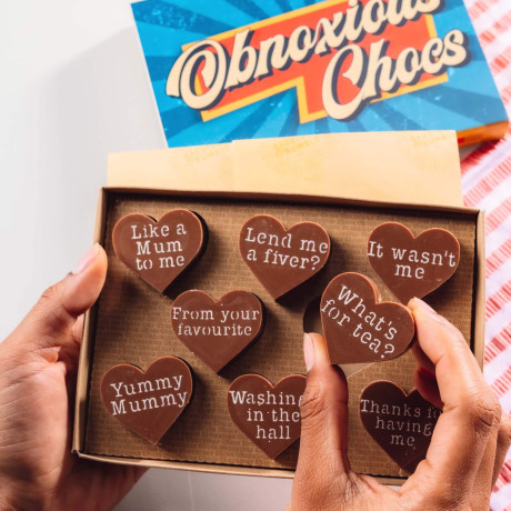 Bagstock & Bumble Mum Obnoxious Chocs gift box held up, containing heart-shaped Fairtrade chocolates with funny slogans, the ultimate treat for mums who deserve more than a card.