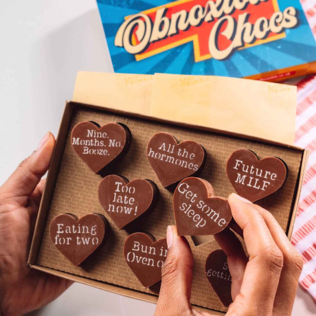 Bagstock & Bumble Obnoxious Chocs gift box packed with heart-shaped Fairtrade Belgian chocolate and sarcastic pregnancy phrases like 'Future MILF', a hilarious gift for mums-to-be.