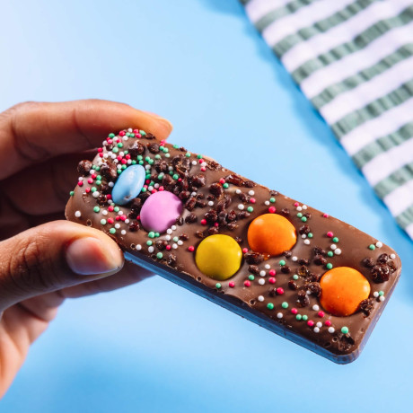 Small milk chocolate bar loaded with chocolate beans and colourful sprinkles.